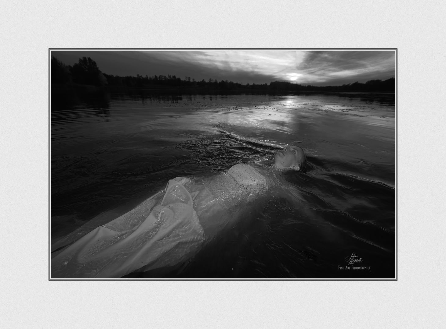 A black and white photograh of a bride floating on water.