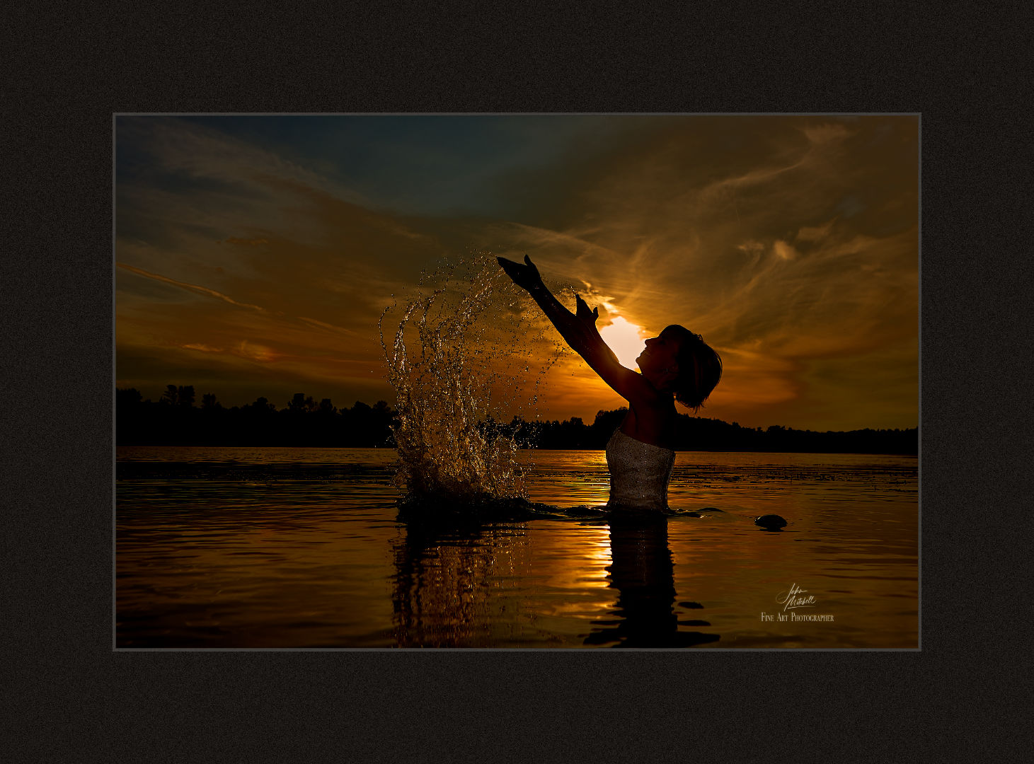 Colour silhouette against the sunset of a bride splashing water in a lake